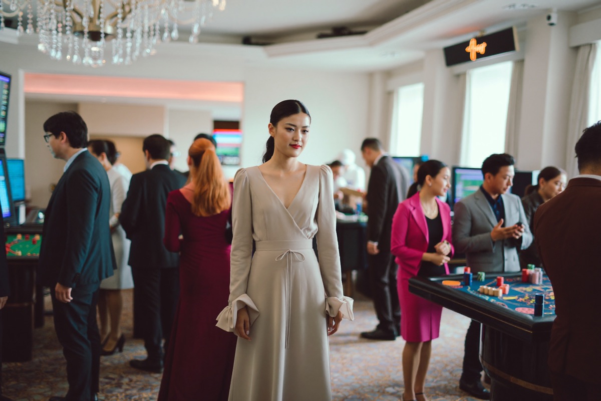Wide view across a busy casino room of gaming tables and guests