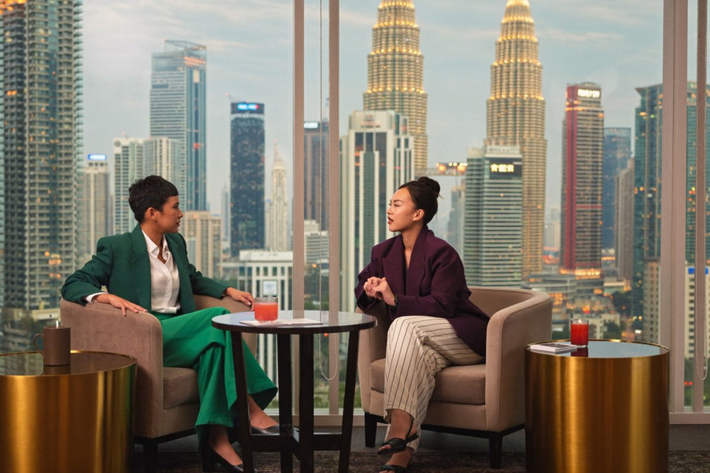 A Kuala Lumpur hotel lounge at dusk with the lit city towers in the window