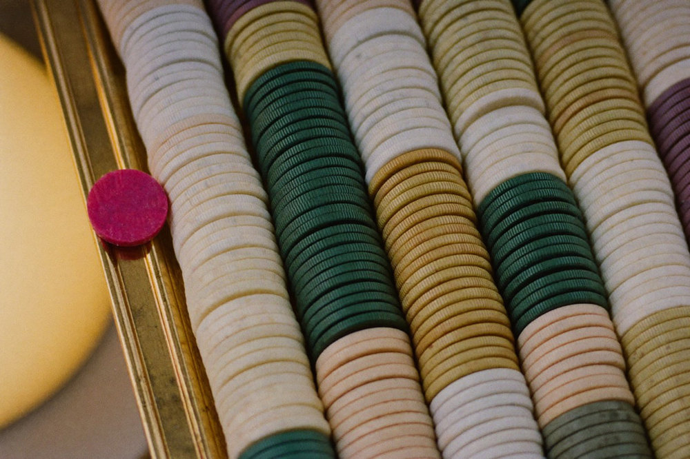 A brass tray of neatly stacked gaming chips on a stone counter under a lamp
