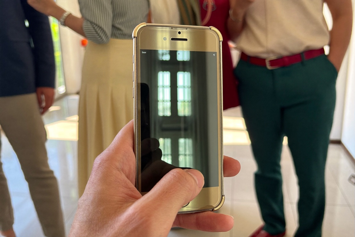 A hand holding a phone with the screen switched off in a sunlit room