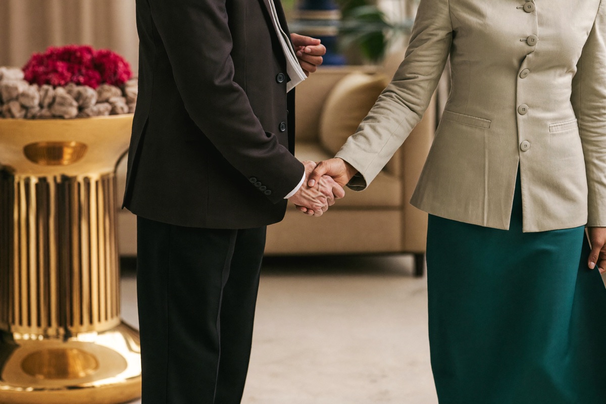 A host in a dinner jacket greeting two arriving guests at a casino entrance
