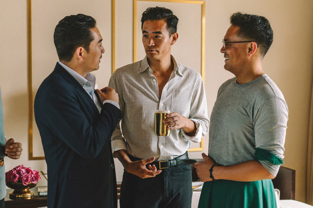 Three men in their late thirties talking together in a warm lounge